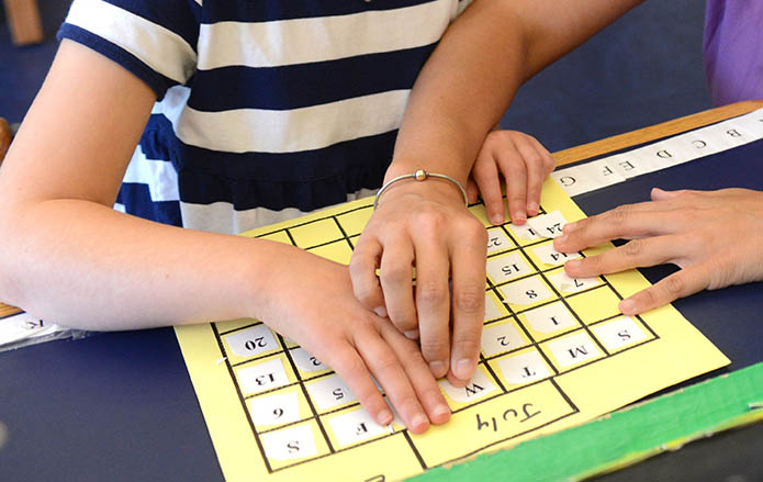 Two pairs of hands use tactile signing.