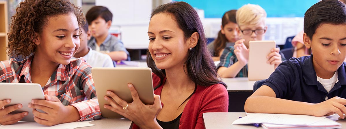 A teacher works with a student using computer tablets.